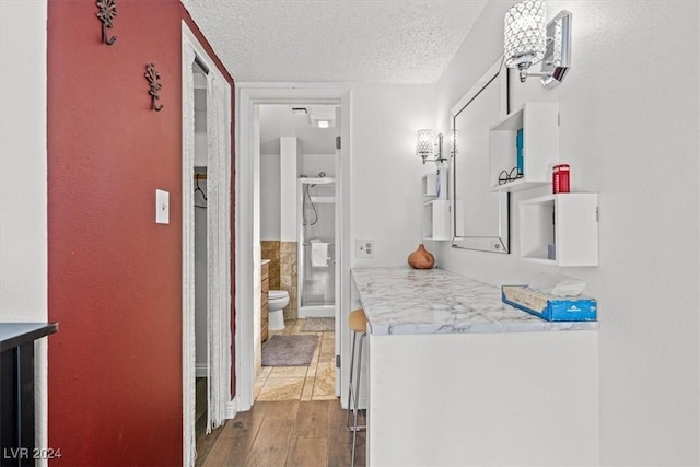 bathroom featuring vanity, wood-type flooring, a textured ceiling, and toilet