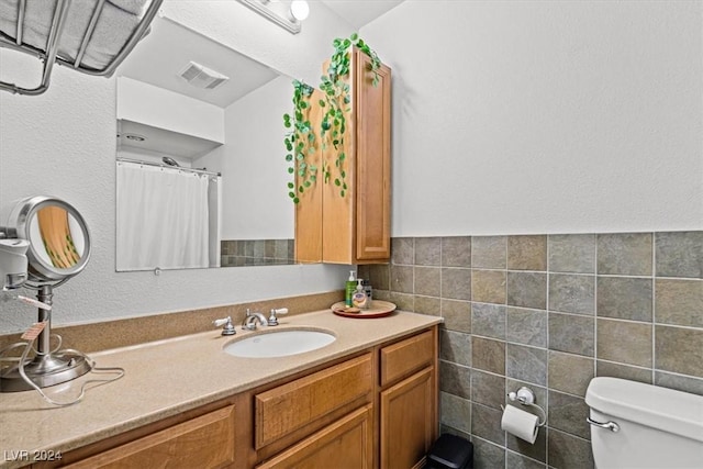 bathroom featuring vanity, tile walls, and toilet