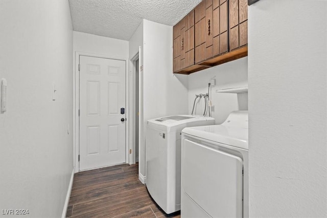 laundry area with washer and dryer, a textured ceiling, dark hardwood / wood-style flooring, and cabinets