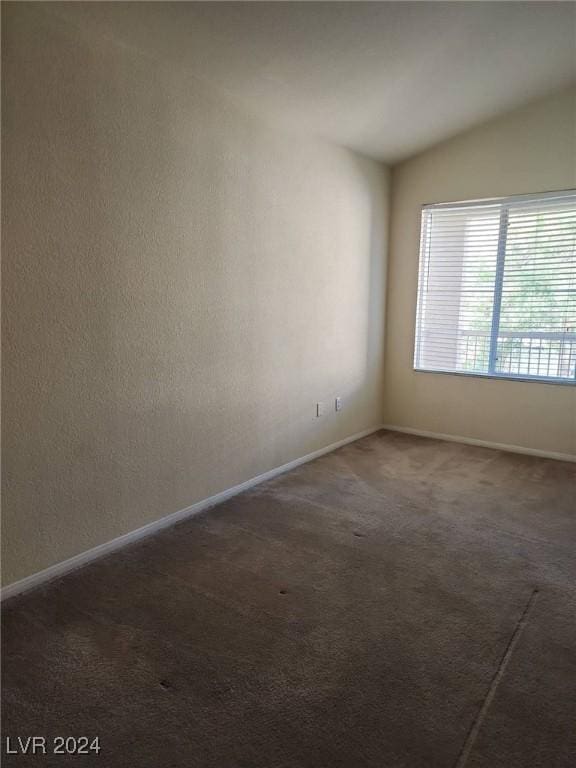 carpeted spare room with vaulted ceiling