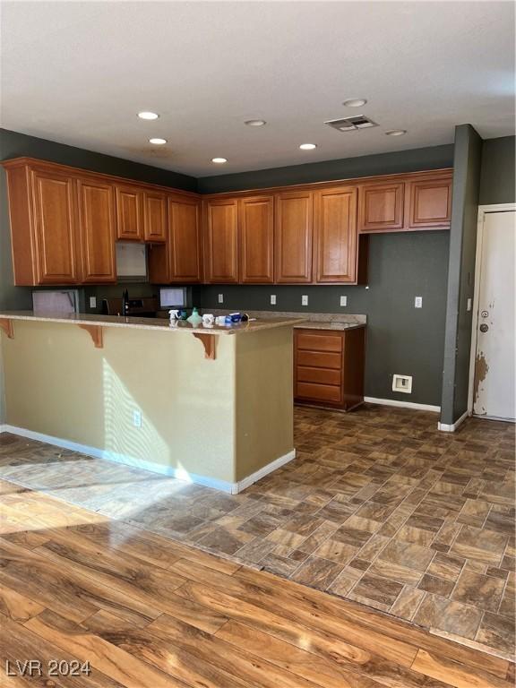 kitchen with dark hardwood / wood-style flooring, kitchen peninsula, and a breakfast bar area