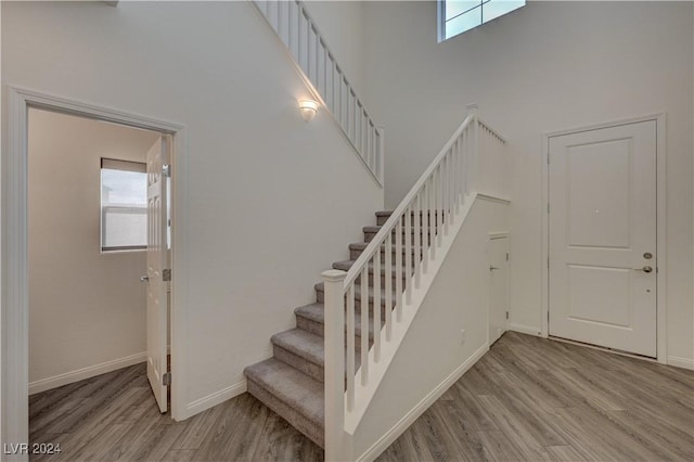 stairs with hardwood / wood-style floors, a healthy amount of sunlight, and a high ceiling