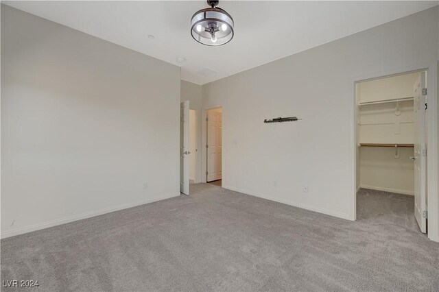 unfurnished bedroom featuring light colored carpet, a spacious closet, and a closet