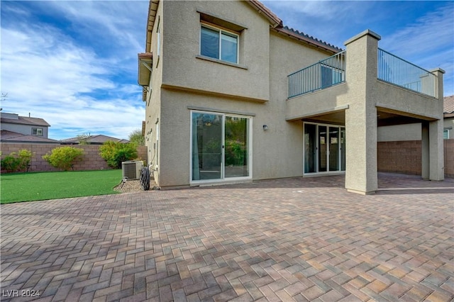 back of property with cooling unit, a balcony, and a patio