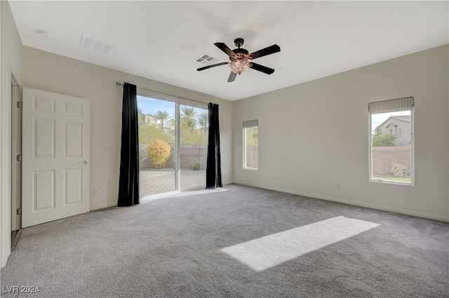 empty room featuring light colored carpet, a wealth of natural light, and ceiling fan