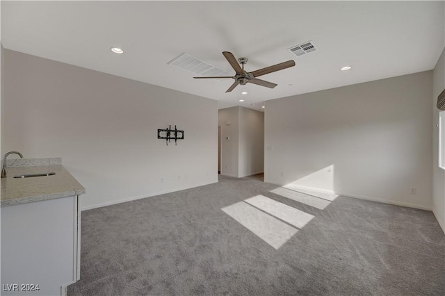 empty room featuring light colored carpet, ceiling fan, and sink