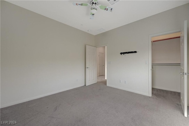 unfurnished bedroom featuring a spacious closet, light carpet, and a closet