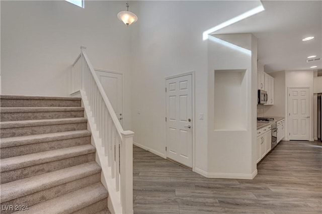 staircase featuring hardwood / wood-style flooring and a towering ceiling