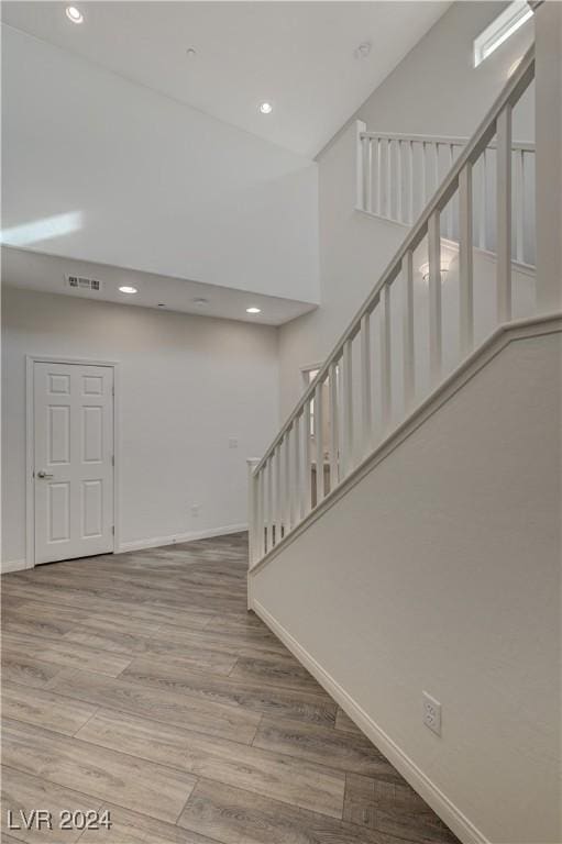 stairs with a towering ceiling and wood-type flooring