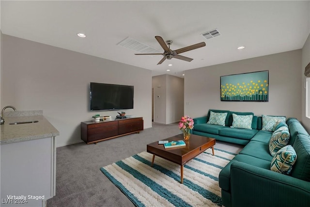 carpeted living room with ceiling fan and sink