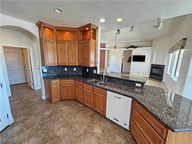 kitchen with ceiling fan, dishwasher, sink, tasteful backsplash, and a premium fireplace