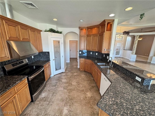 kitchen featuring backsplash, stainless steel electric range oven, dark stone counters, and extractor fan