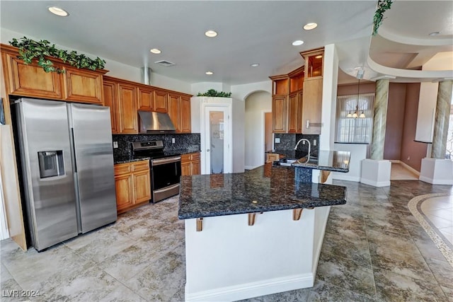 kitchen with a kitchen bar, dark stone counters, stainless steel appliances, and range hood