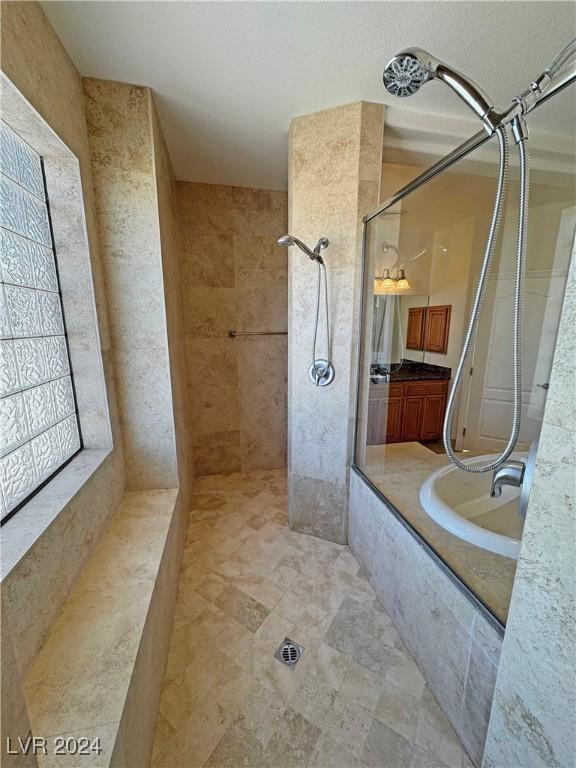 bathroom with a tile shower and vanity