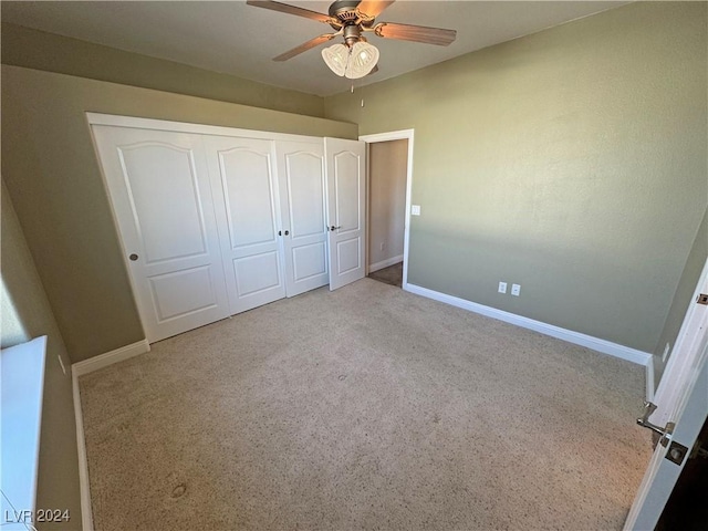 unfurnished bedroom featuring light carpet, a closet, and ceiling fan