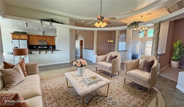 tiled living room with a tray ceiling, french doors, a towering ceiling, and ceiling fan with notable chandelier