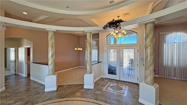 carpeted foyer featuring a chandelier, french doors, and decorative columns