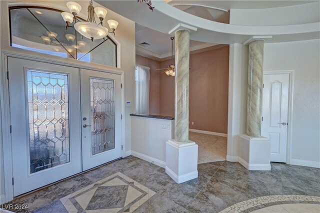 foyer with ceiling fan with notable chandelier, decorative columns, and french doors