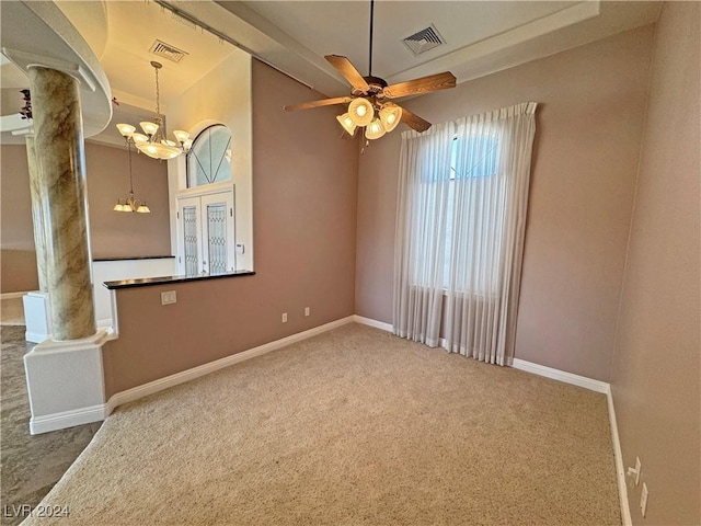 carpeted empty room with ceiling fan with notable chandelier and ornate columns