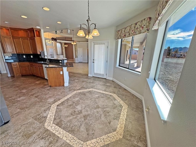 kitchen with kitchen peninsula, tasteful backsplash, a breakfast bar, pendant lighting, and a chandelier