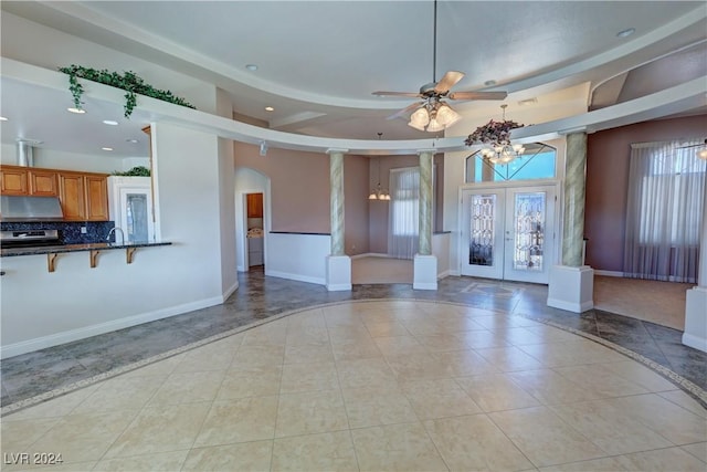 unfurnished living room featuring decorative columns, plenty of natural light, light tile patterned floors, and french doors