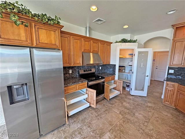 kitchen with ventilation hood, stainless steel appliances, dark stone counters, and tasteful backsplash