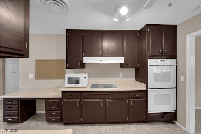 kitchen featuring white appliances, light countertops, under cabinet range hood, and dark brown cabinetry