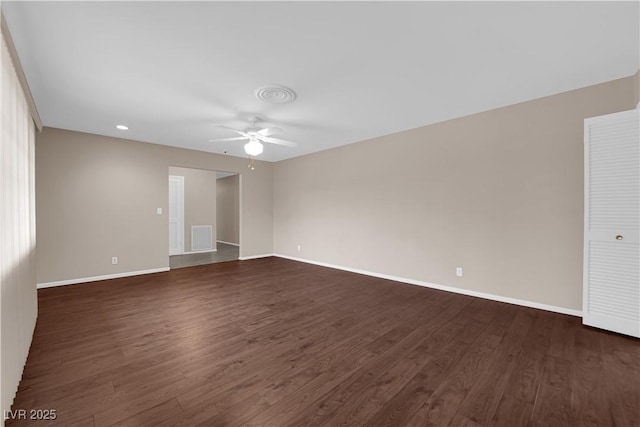 empty room with visible vents, dark wood-style floors, a ceiling fan, and baseboards