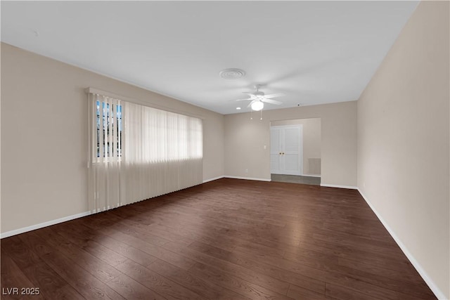 unfurnished room featuring dark wood finished floors, visible vents, baseboards, and a ceiling fan