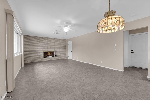 unfurnished living room featuring baseboards, brick wall, a fireplace, and ceiling fan