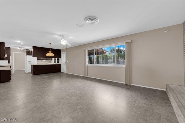 unfurnished living room with visible vents, baseboards, and ceiling fan