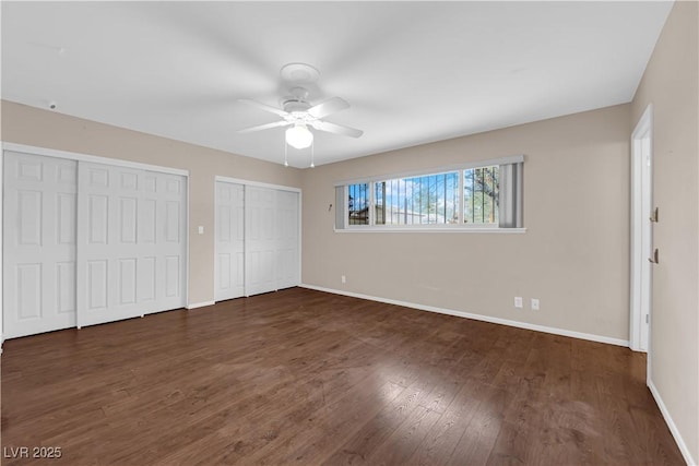 unfurnished bedroom featuring a ceiling fan, wood finished floors, multiple closets, and baseboards