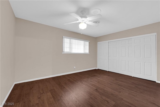 unfurnished bedroom with a closet, baseboards, dark wood finished floors, and a ceiling fan