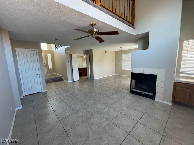 unfurnished living room with ceiling fan with notable chandelier, light tile patterned flooring, and a textured ceiling