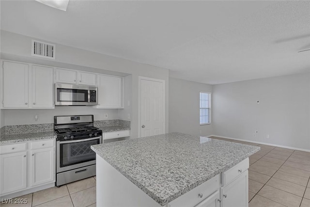 kitchen with white cabinetry, stainless steel appliances, a center island, and light tile patterned floors