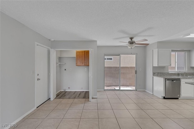 kitchen with light tile patterned flooring, sink, stainless steel dishwasher, ceiling fan, and white cabinets