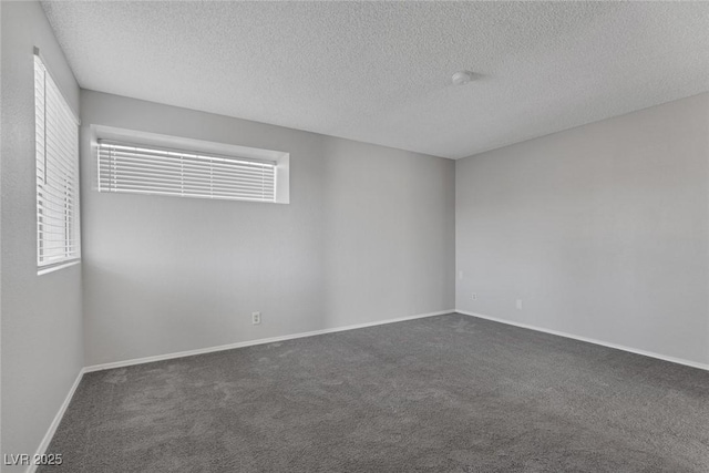 unfurnished room with dark carpet and a textured ceiling