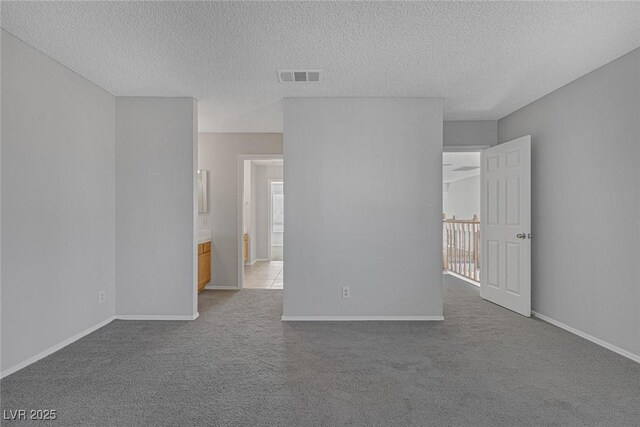 unfurnished room featuring a textured ceiling and carpet