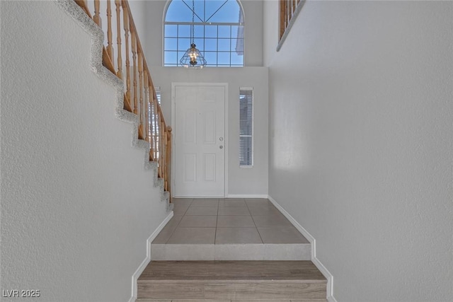 foyer entrance with tile patterned flooring and a towering ceiling