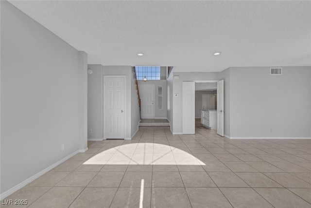 empty room with a textured ceiling and light tile patterned flooring