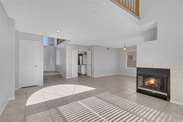 unfurnished living room featuring a multi sided fireplace and light tile patterned floors