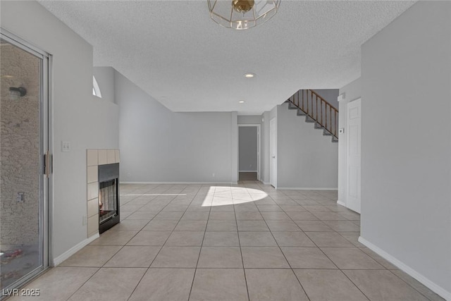 unfurnished living room featuring a tiled fireplace, light tile patterned floors, and a textured ceiling