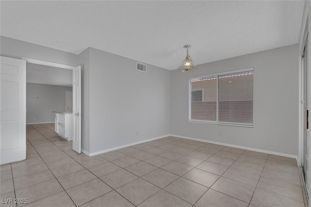 empty room with light tile patterned flooring and a textured ceiling