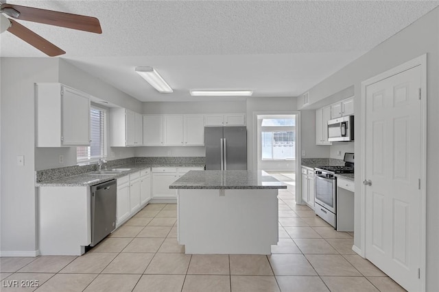 kitchen with sink, stainless steel appliances, a center island, white cabinets, and light tile patterned flooring