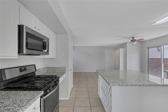 kitchen featuring light stone counters, a center island, light tile patterned floors, appliances with stainless steel finishes, and white cabinets