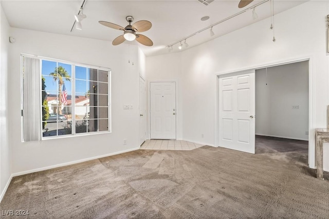 carpeted spare room with ceiling fan, high vaulted ceiling, and track lighting