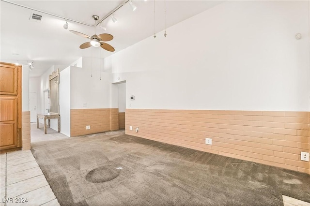 carpeted spare room with ceiling fan, high vaulted ceiling, and track lighting