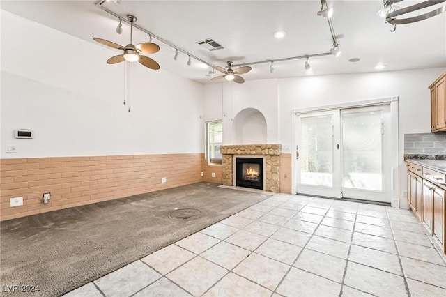 unfurnished living room featuring a fireplace, light tile patterned floors, and ceiling fan