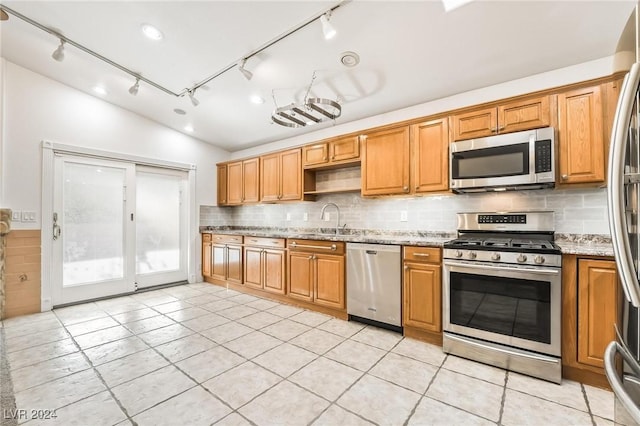 kitchen featuring light stone counters, sink, stainless steel appliances, and vaulted ceiling