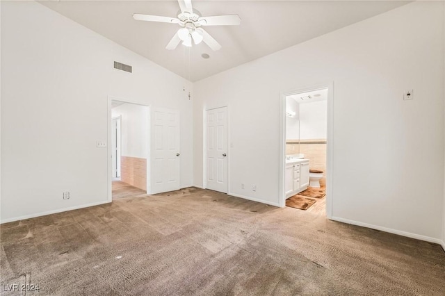 unfurnished bedroom featuring connected bathroom, light carpet, ceiling fan, and high vaulted ceiling